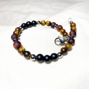 Bracciale Occhio di Tigre e Onice - pietre naturali e acciaio Linea Gimo_Jewels Realizzato con pietre dure di Occhio di Tigre (rosso e giallo) e Onice, con chiusura a moschettone e distanziatori in acciaio anallergico. L'occhio di Tigre Pietra originaria del Sud Africa estratta tuttavia anche in Australia, India, Brasile e Birmania, presenta colori e sfumature molto particolari tanto da essere ampiamente utilizzata in gioielleria. Non s9i tratta di un minerale particolarmente pregiato e questo fa sì che sia rarissimo trovarne in giro di contraffatti. In generale si presenta di colore giallo brunastro con striature scure, ma ne esistono anche colori che virano dal blu al grigio al verde (occhio di falco) e dal colore rossastro o mogano (occhio di tigre rosso).