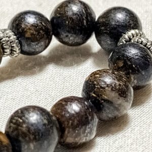 Bracciale elastico in pietra naturale di bronzite Linea Gimo_Jewels Realizzato con pietre naturali di bronzite, il bracciale si adatta bene al polso grazie al suo elastico morbido ma resistente e anallergico. La bronzite fa parte del gruppo di minerali pirosseni ed è una pietra naturale di colore marrone con toni dorati e ramati. Si tratta di una varietà ferrifera di enstatite che, a causa di una parziale alterazione, ha acquisito una lucentezza submetallica simile al bronzo. Conosciuta già al tempo dei Romani, che le attribuivano proprietà medicinali e protettive, la bronzite è oggi ampiamente utilizzata e apprezzata soprattutto in gioielleria per realizzare ornamenti, bracciali e ciondoli.