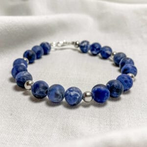 Bracciale in acciaio e pietra naturale di Sodalite Blu Linea Gimo_Jewels Realizzato con pietre dure di Sodalite Blu (opaca), con chiusura a moschettone e distanziatori in acciaio anallergico. La sodalite prende il nome dall’alto contenuto di sodio e in genere si forma quando le rocce ricche di alluminio e di silicio vengono invase dal basso da acque ricche di cloruro di sodio. La gamma dei colori della pietra varia dal blu intenso al blu chiaro fino al bianco.